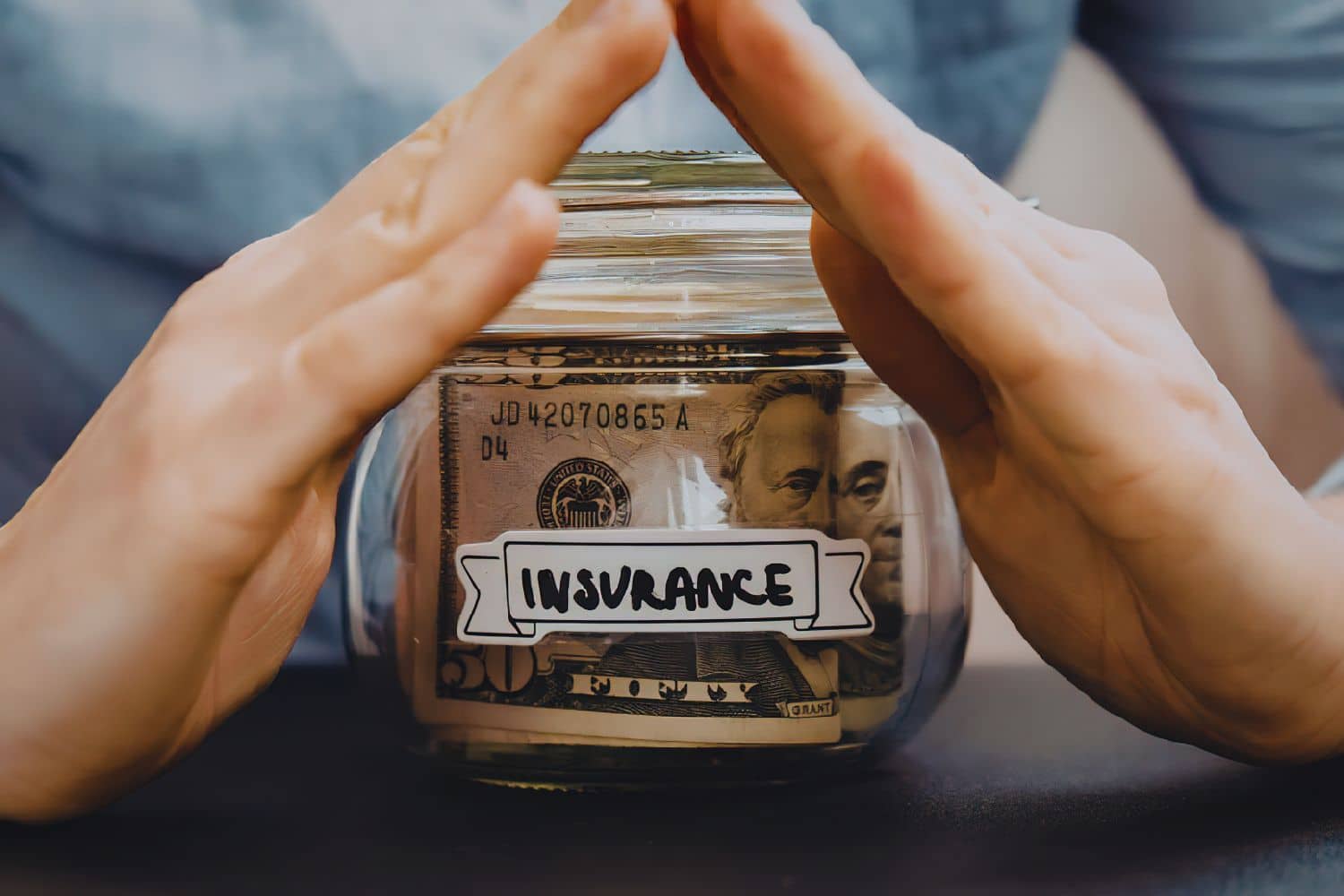 Mains protégeant bocal d’argent étiqueté assurance