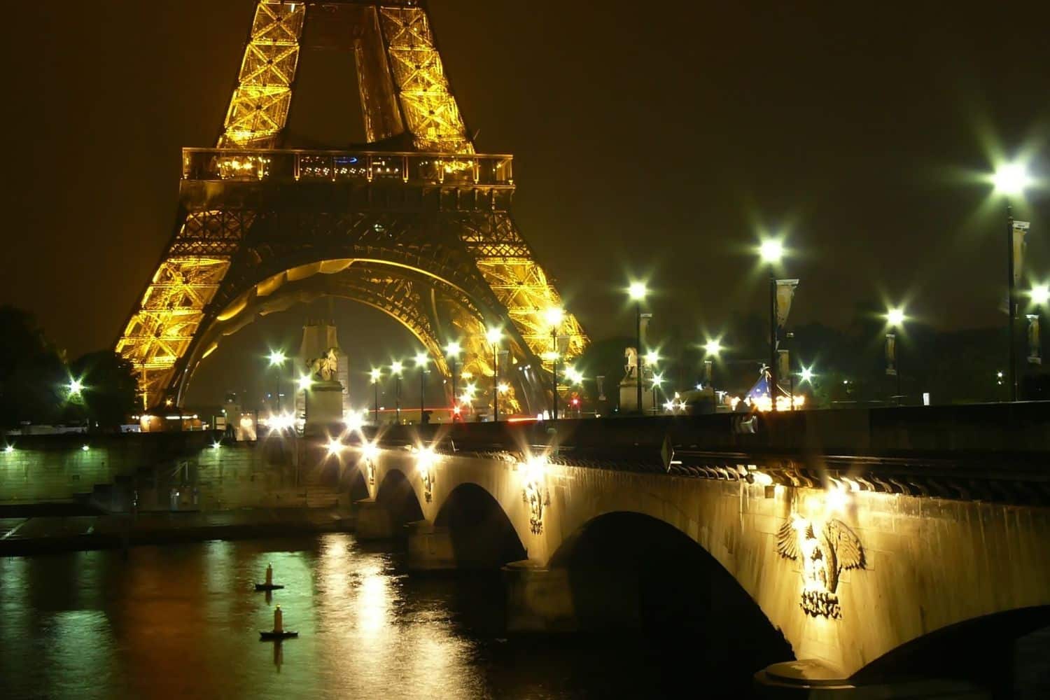 Tour Eiffel illuminée la nuit depuis un pont