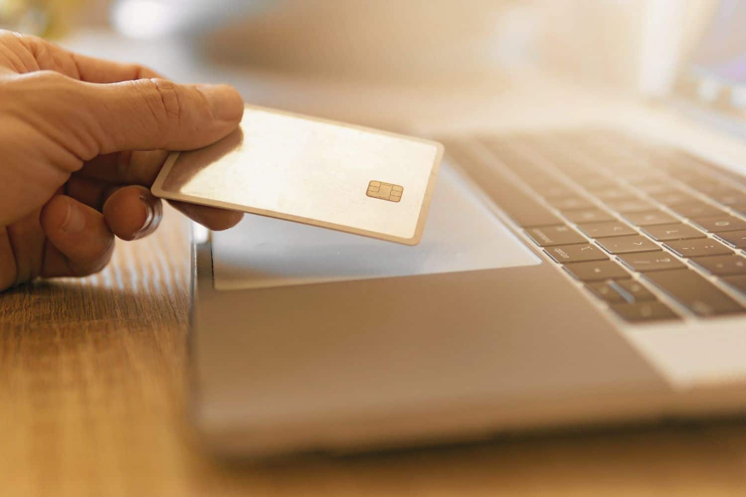 Main tenant carte bancaire au-dessus d’un ordinateur portable