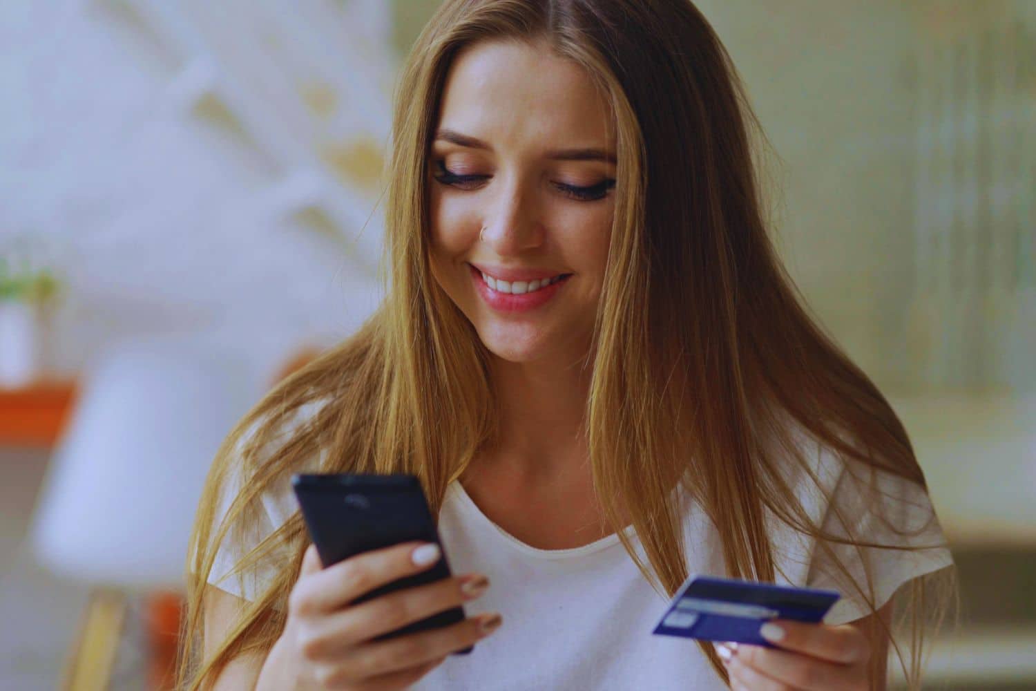 Femme souriante utilisant smartphone et carte bancaire